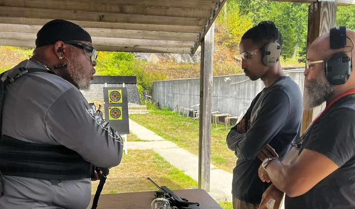 Damon Wright talking with two students beside a range bench